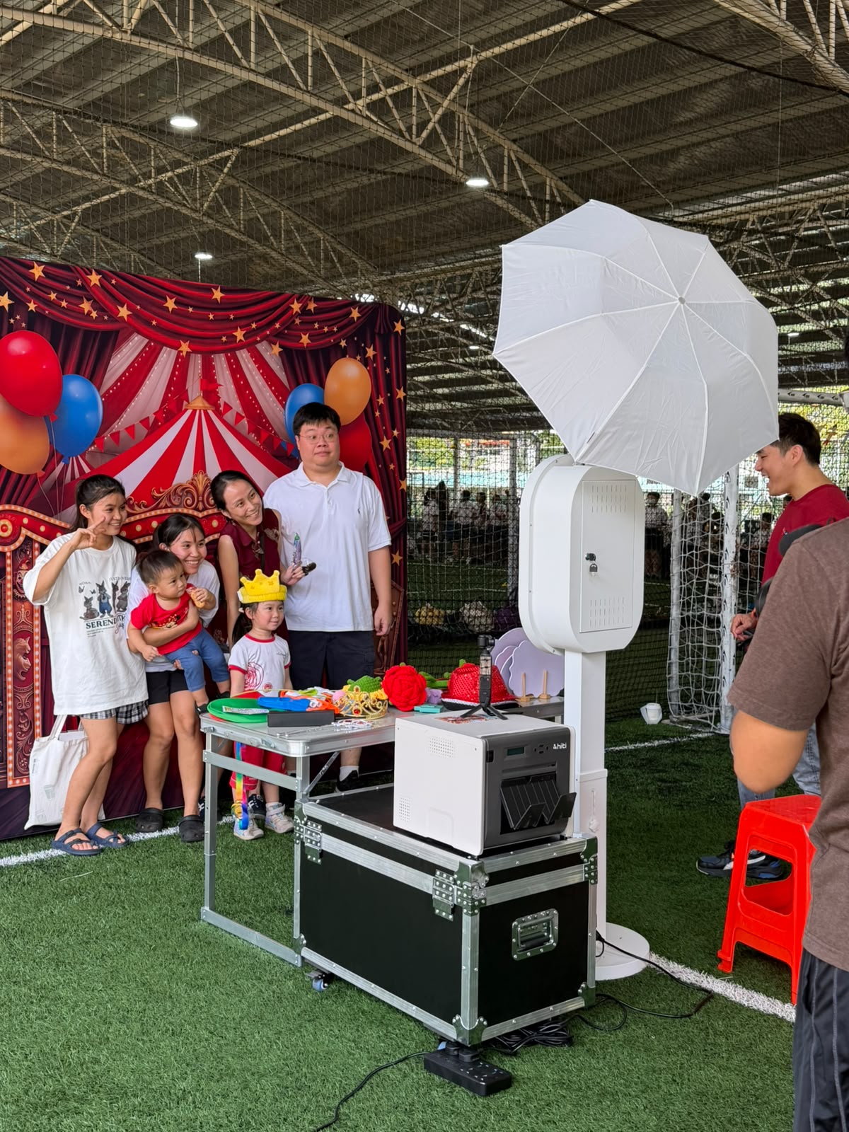 Family posing at AI Booth SG's real booth with umbrella lighting, props and printer