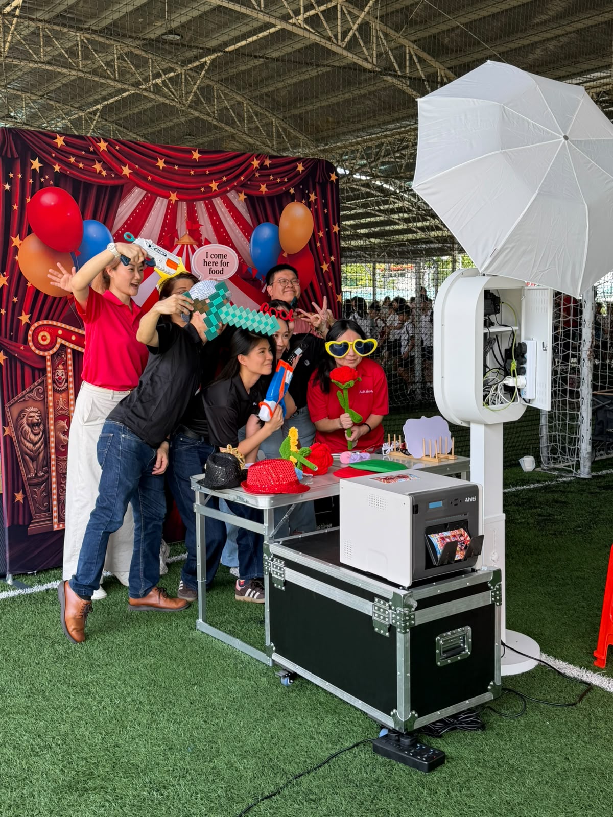 Guests using colourful props beside the photobooth and HiTi printer at a family day