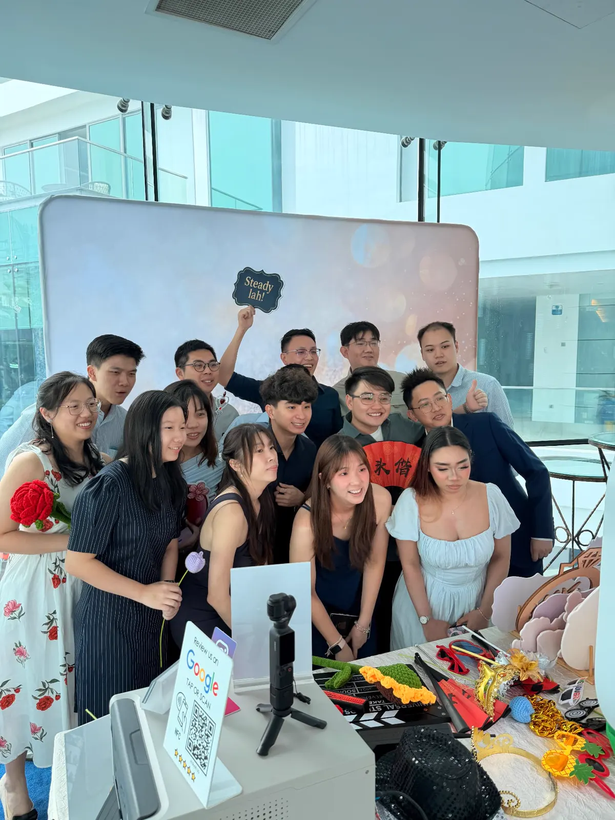 A large group of wedding guests crowding into the photobooth with props